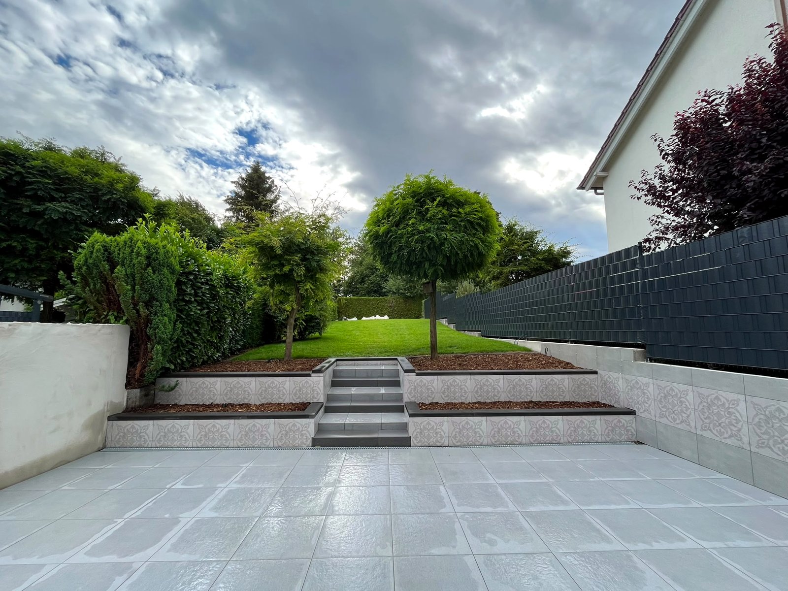 Nachher: neu aufgebaute Stützmauern mit Ziersteinen, Treppe und Beeten