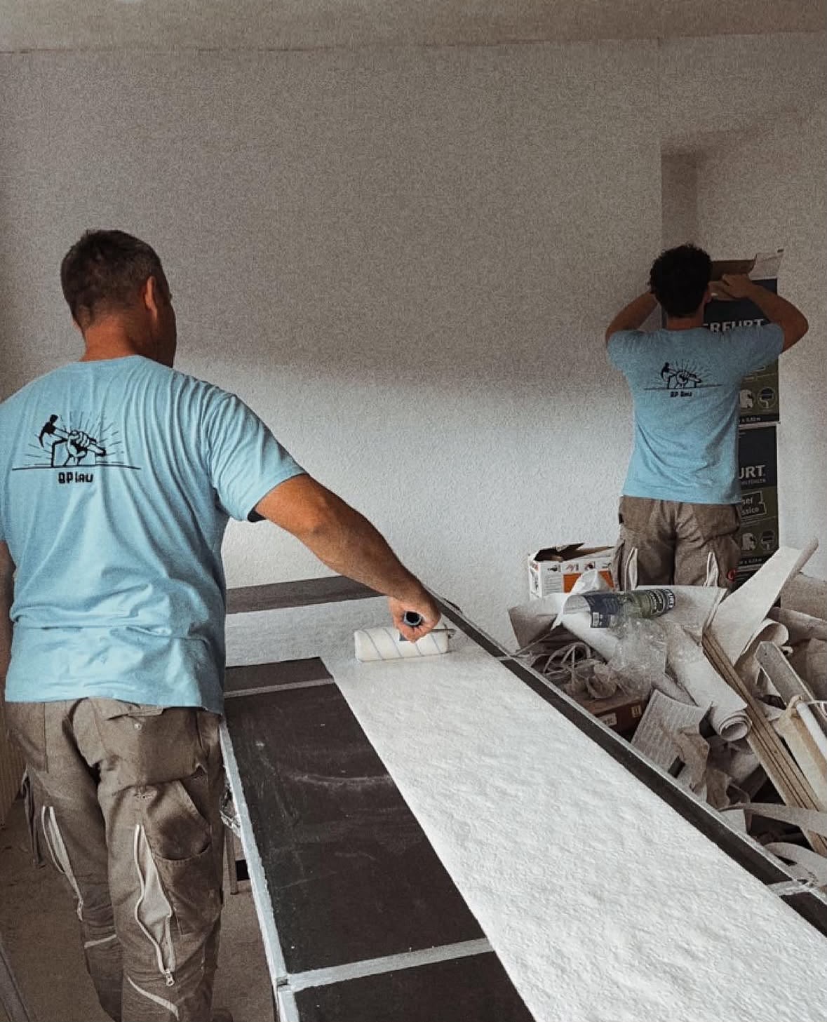 Zwei Handwerker von BP Bau bringen zu zweit eine Wandbeschichtung an